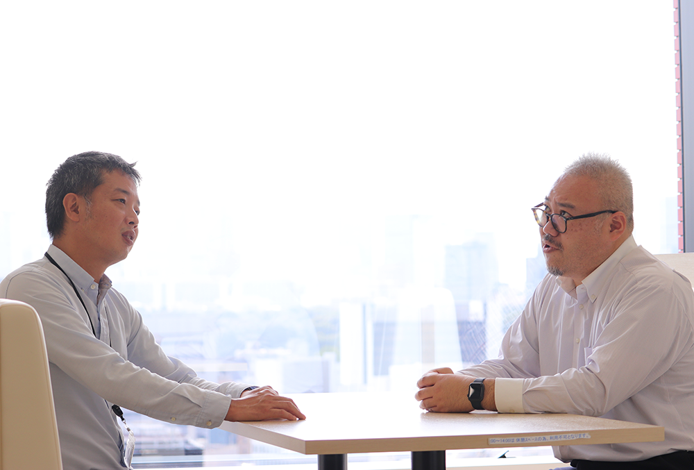 稲内圭(写真左)と社内で打ち合わせする水口